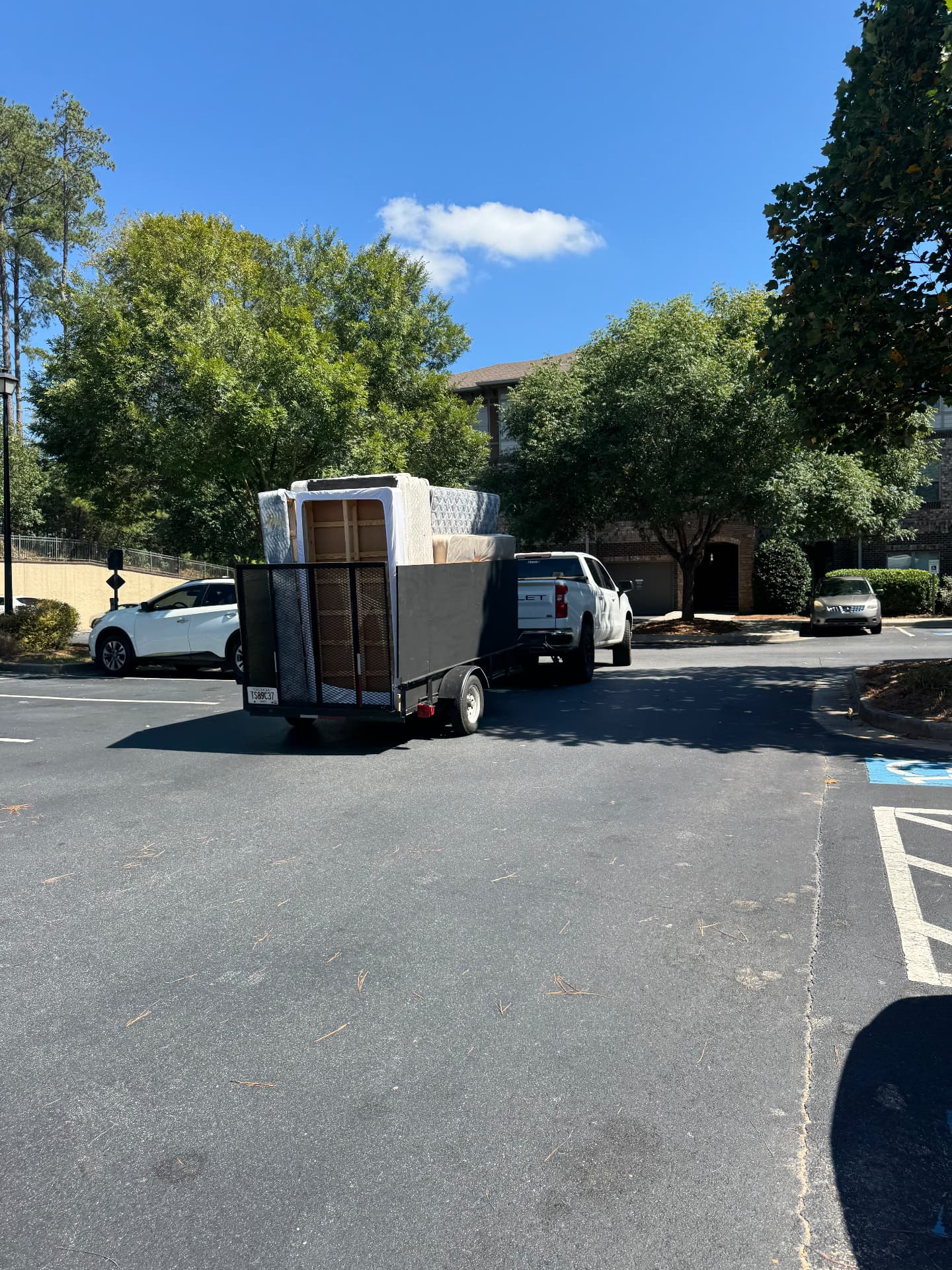 A loaded 5x10 junk removal trailer hitched to a white pickup truck